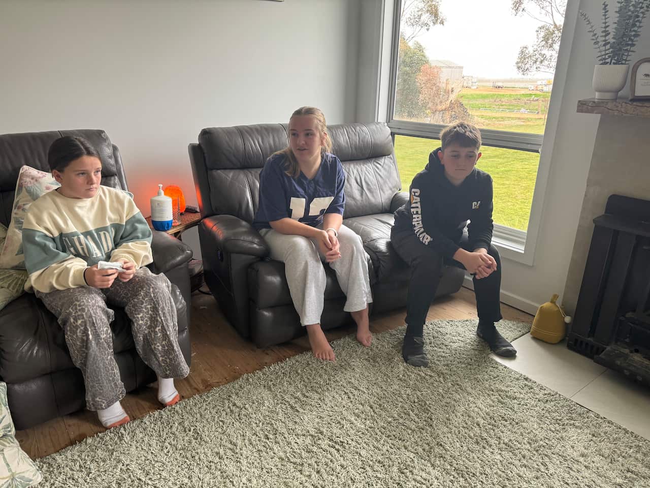Three children sitting on a lounge looking concerned.