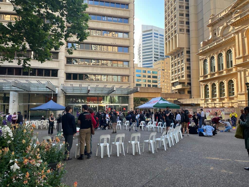 White plastic chairs are placed in a circle in front of Sydney's Town Hall