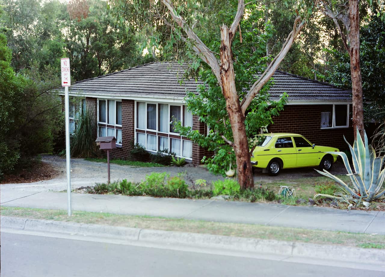 A yellow car parked near a house.