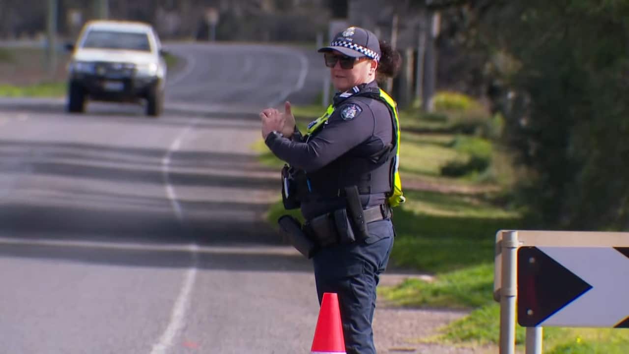 A police officer stands on a road. 