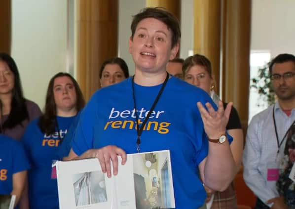 A woman talks animatedly as she holds up a book with rental property pictures.
