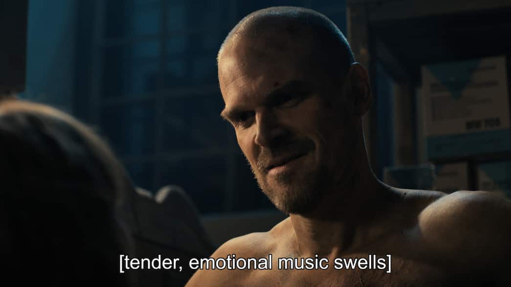 A bald man looks at a woman with closed captions reading "tender, emotional music swells"