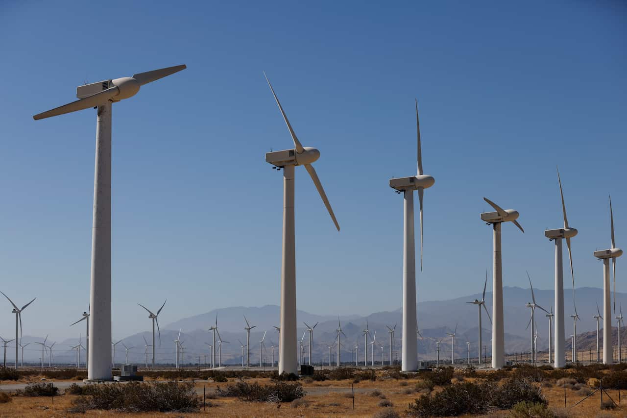 A row of wind turbines in a rural landscape.