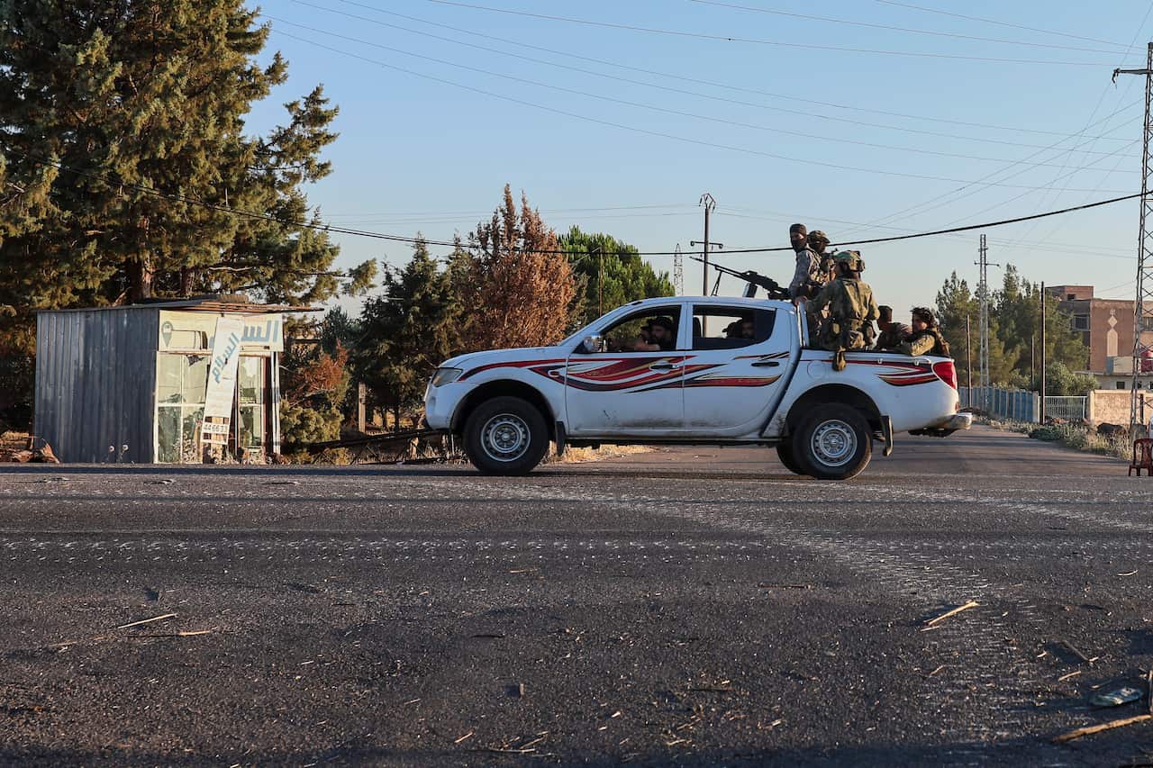 Security forces carrying weapons atop a ute are stationed in a residential area.
