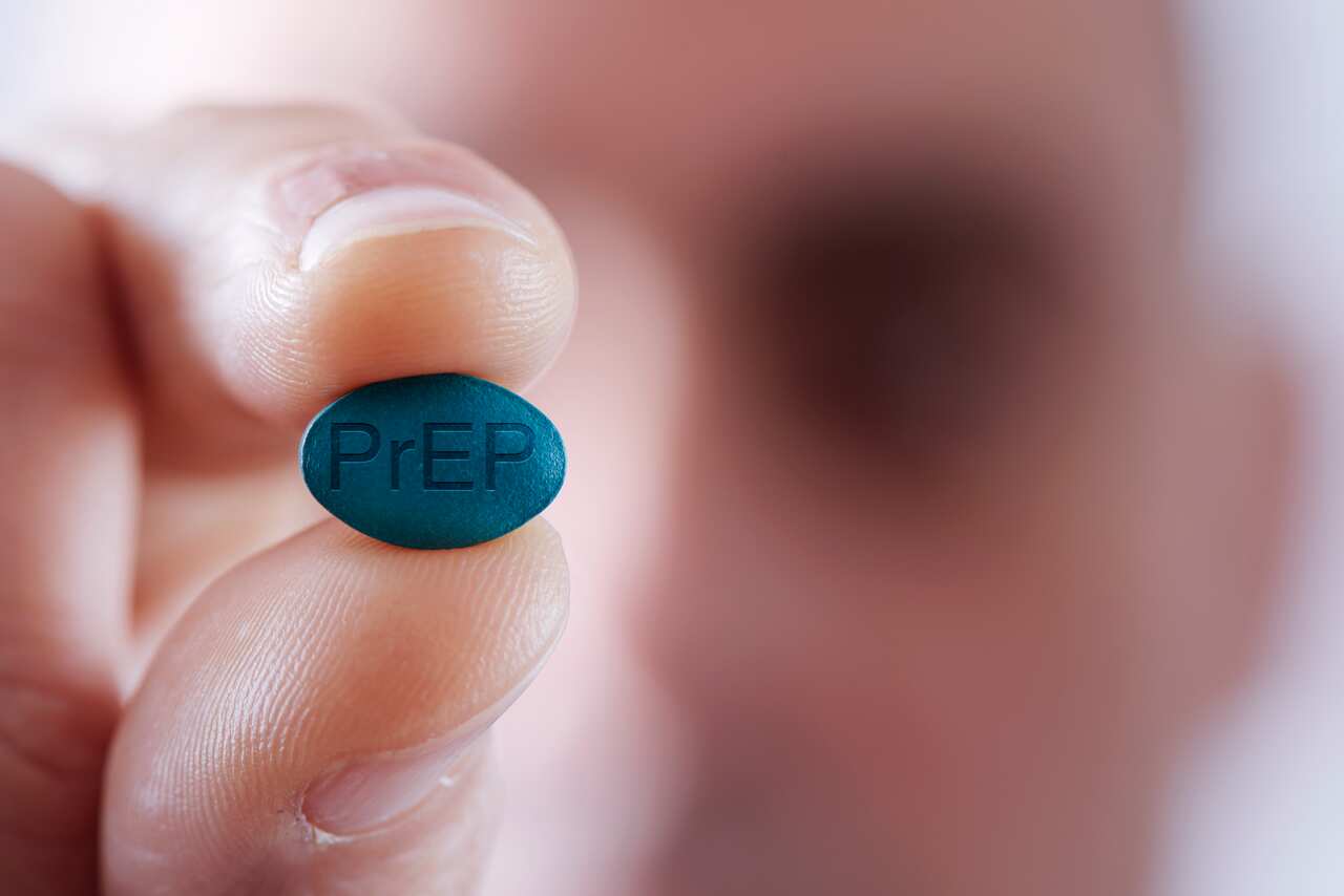 A man holding a PrEP pill between his fingers.