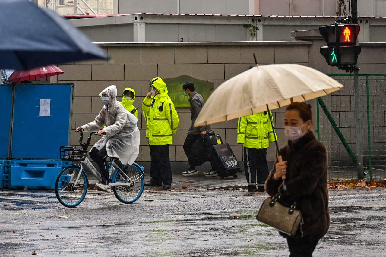 Police on a street standing guard as citizens walk by.