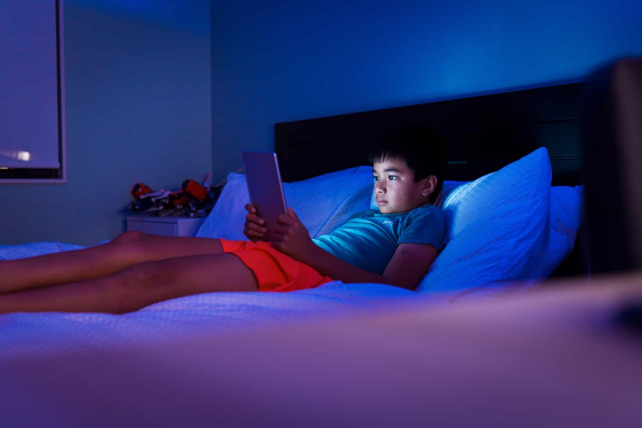 Child watching video on digital tablet at night.
