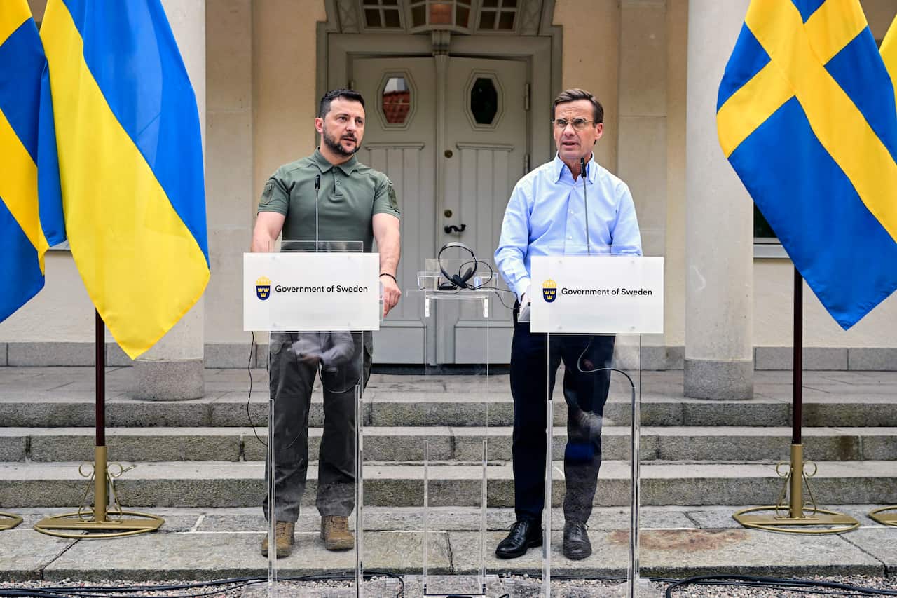 Two men stand in front of podiums at a press conference.