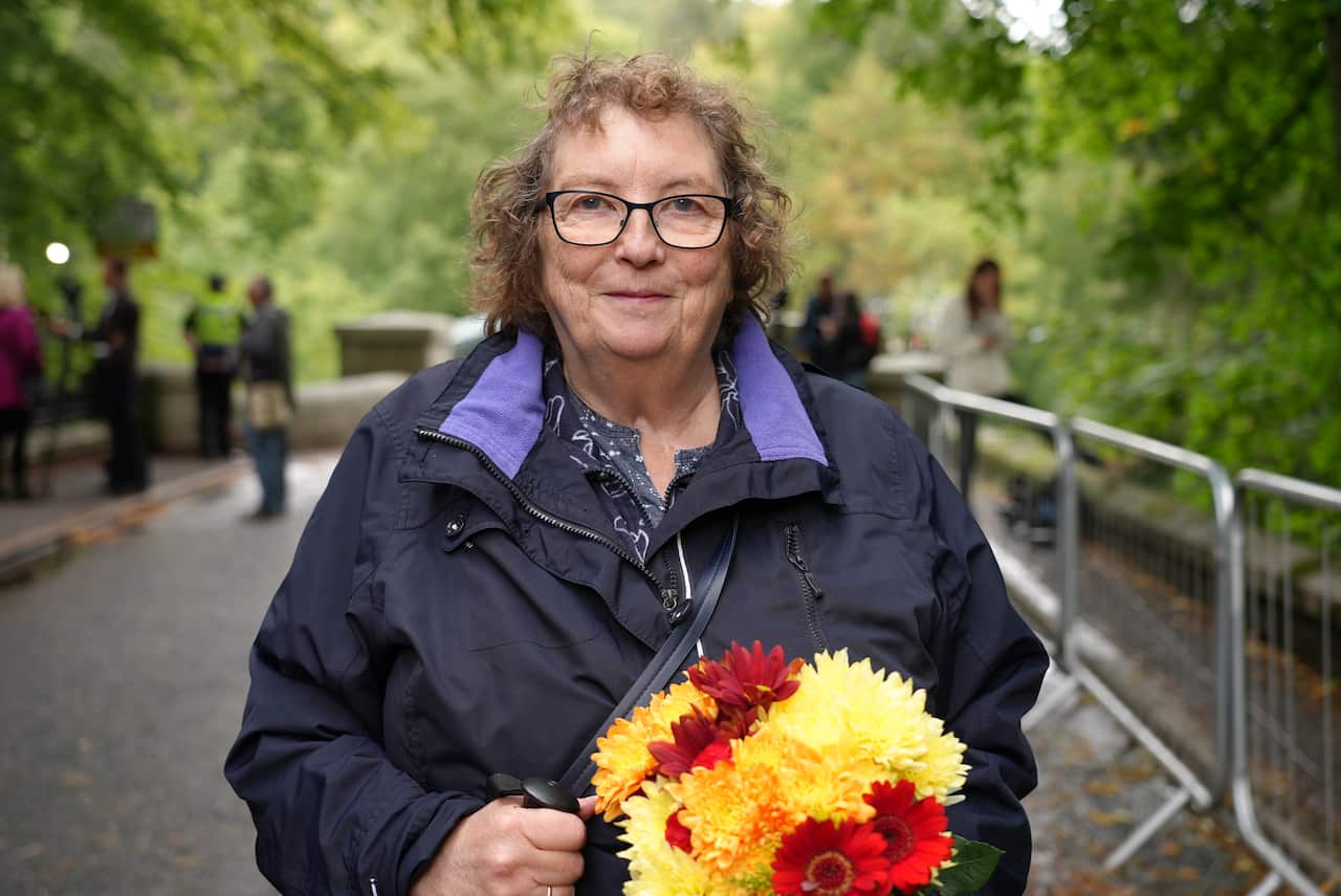 Woman standing in park holding flowers.
