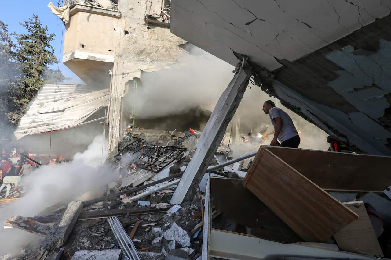 A person looking out at the destruction of nearby buildings.