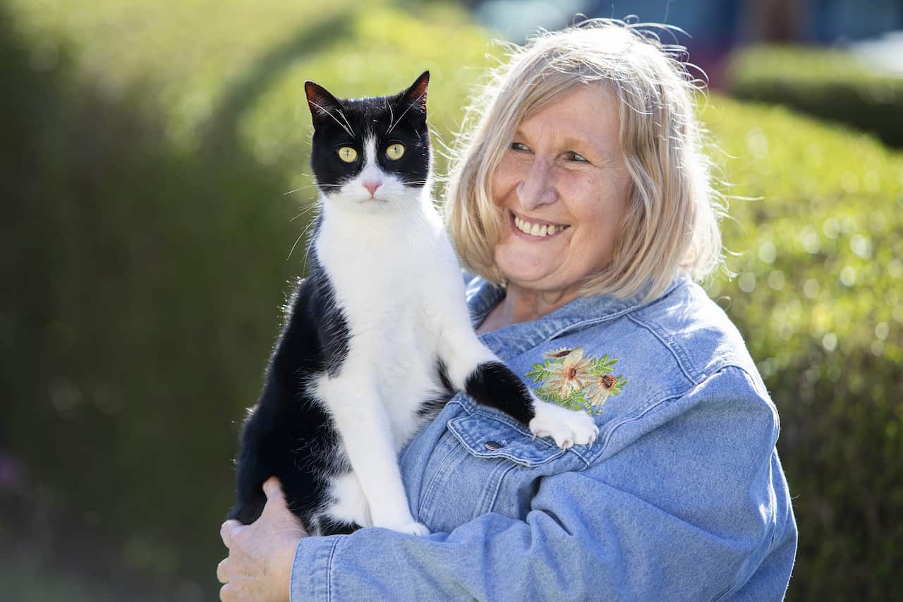 A woman standing outside holding her pet cat.