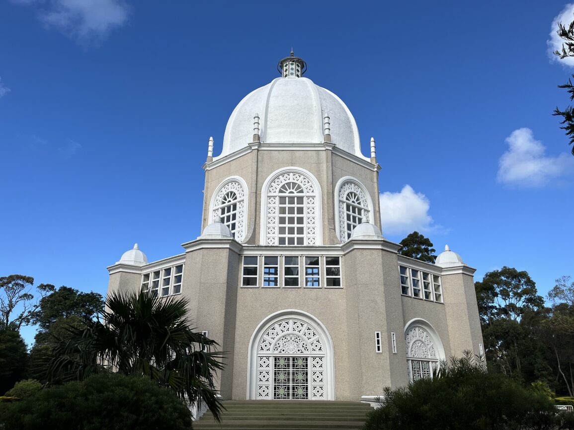 A Baha'i temple with ornate windows against a blue sky. 