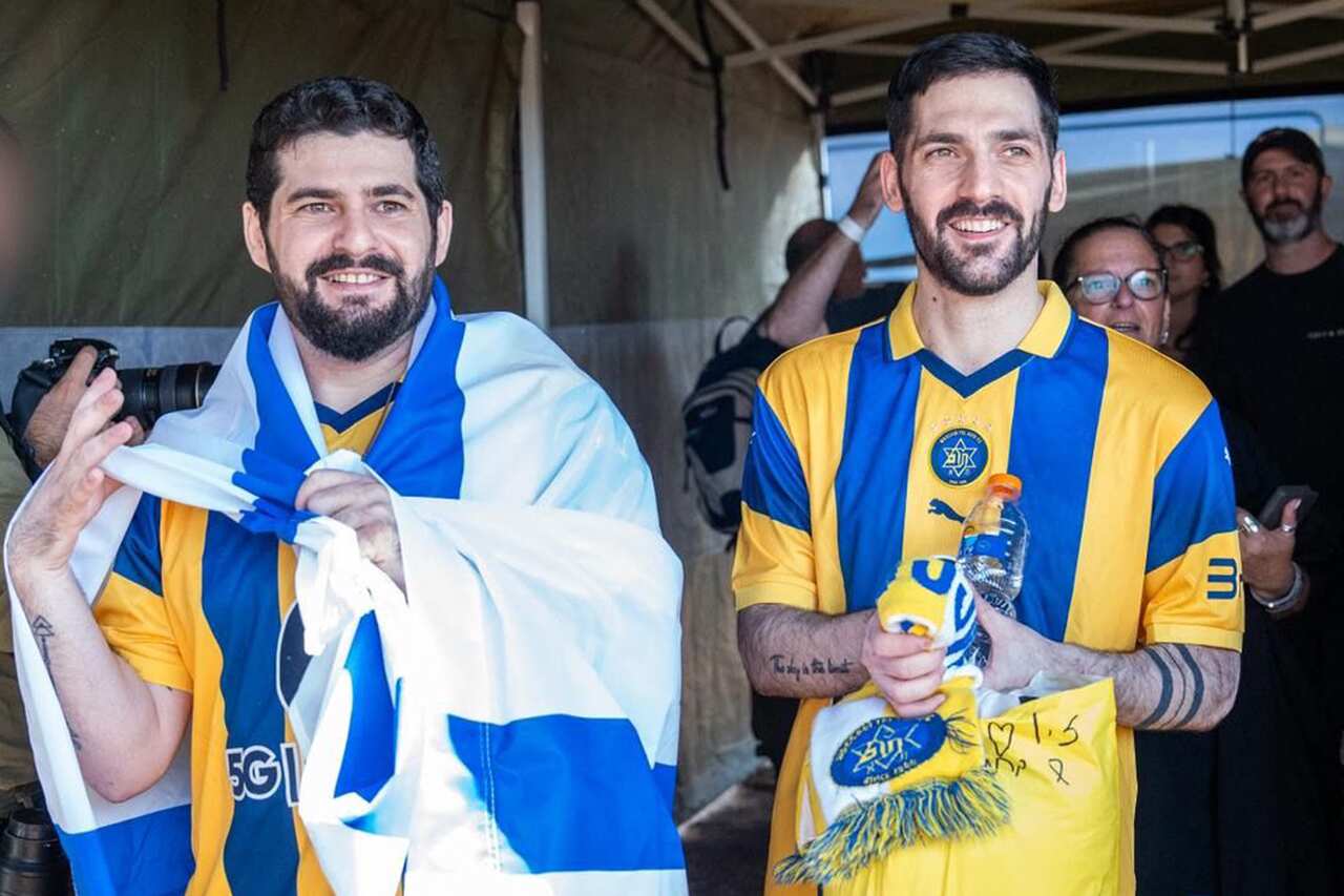 Two men wearing blue and yellow jerseys, with one also draped in an Israeli flag.