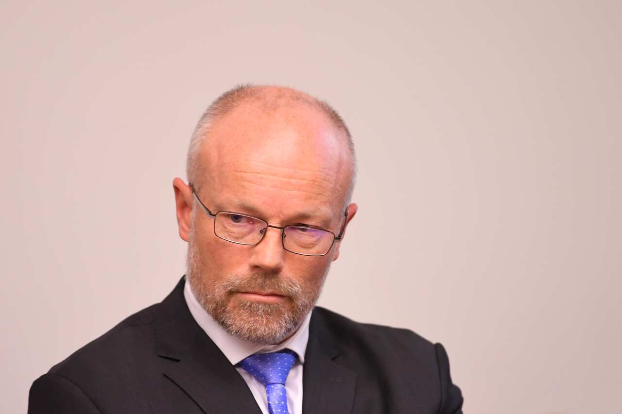 A white middle-aged man in a suit with a serious expression.