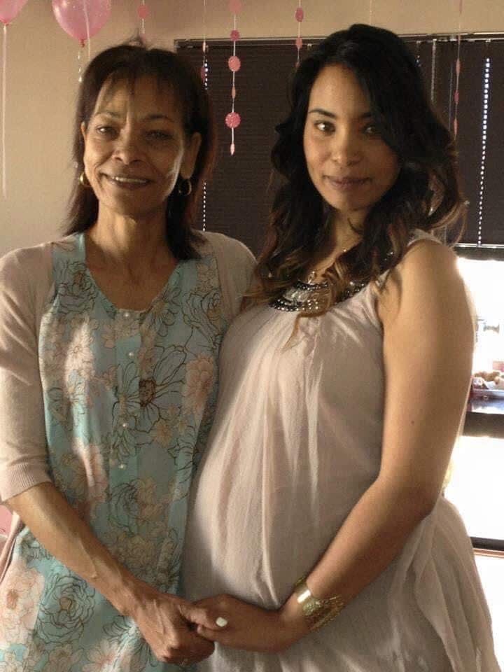 A pregnant Siham stands smiling next to her mother Amina.