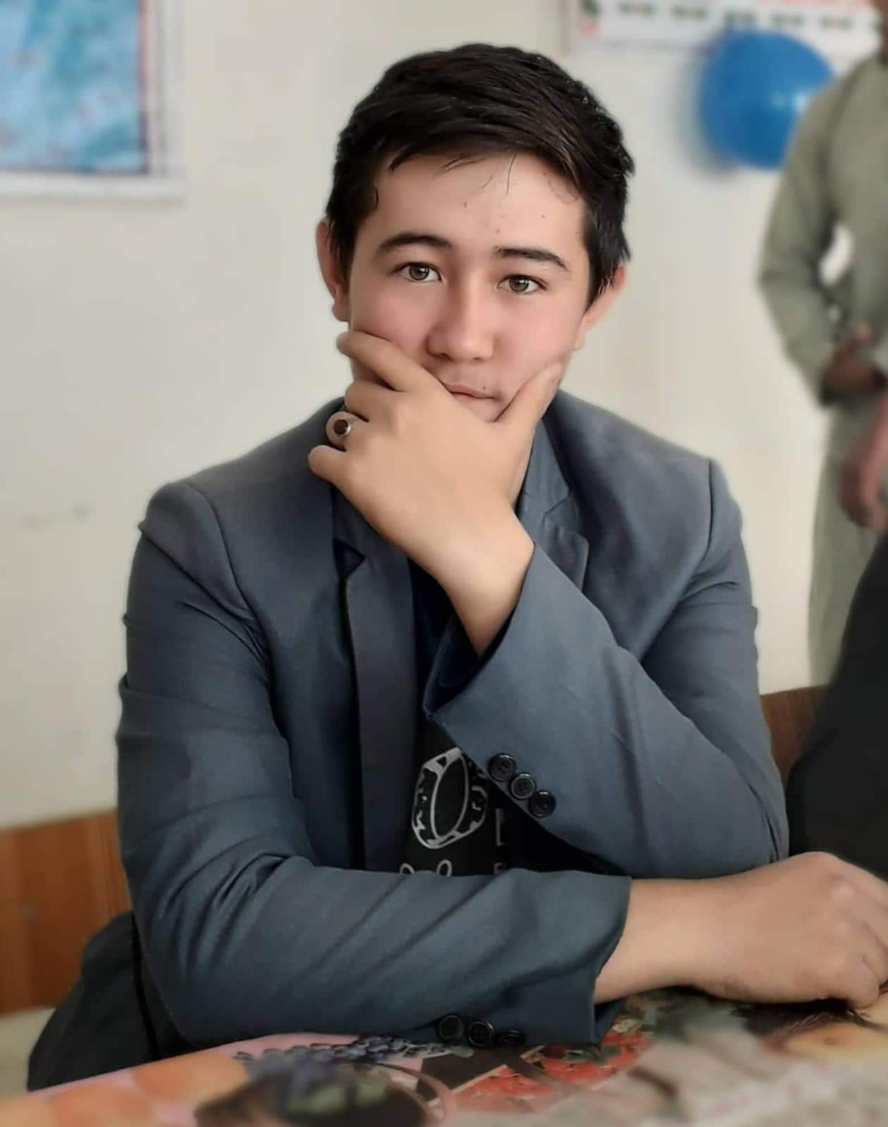 A young man in a suit with his hand over his face