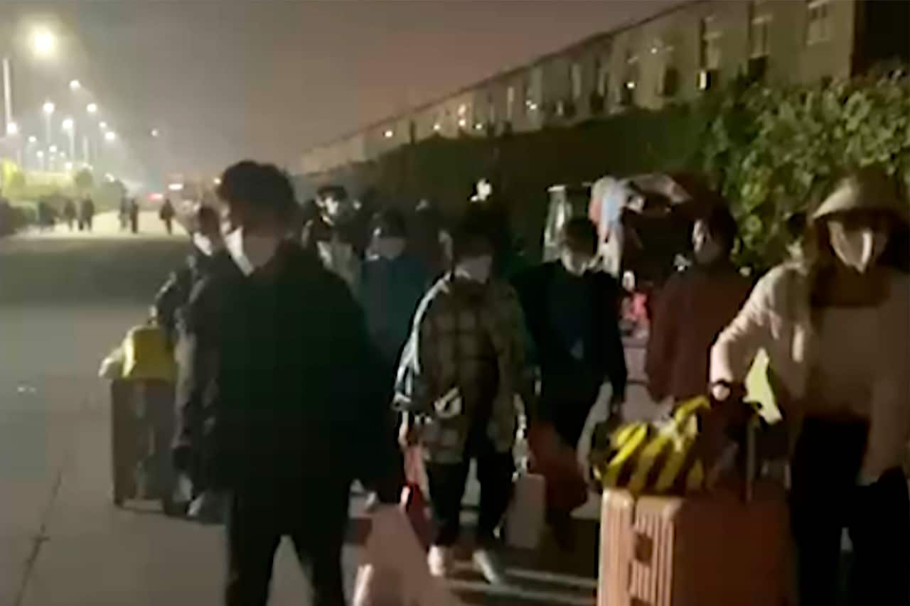 People carrying bags on a street at night