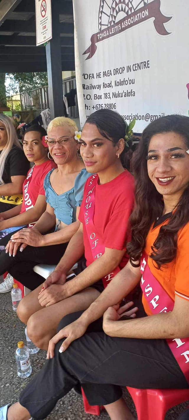 Four people sitting on a bench wearing netball uniforms.