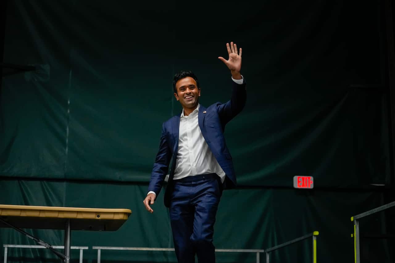 A man wearing formal attires waves as he walks on stage.