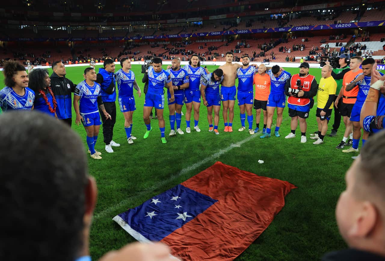 Men in blue jerseys circle around a jersey. 