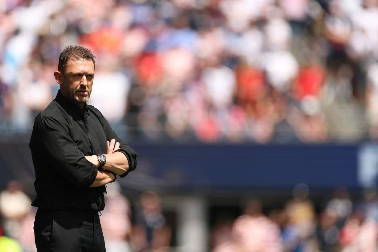 A middle-aged man wearing a black shirt with his arms crossed