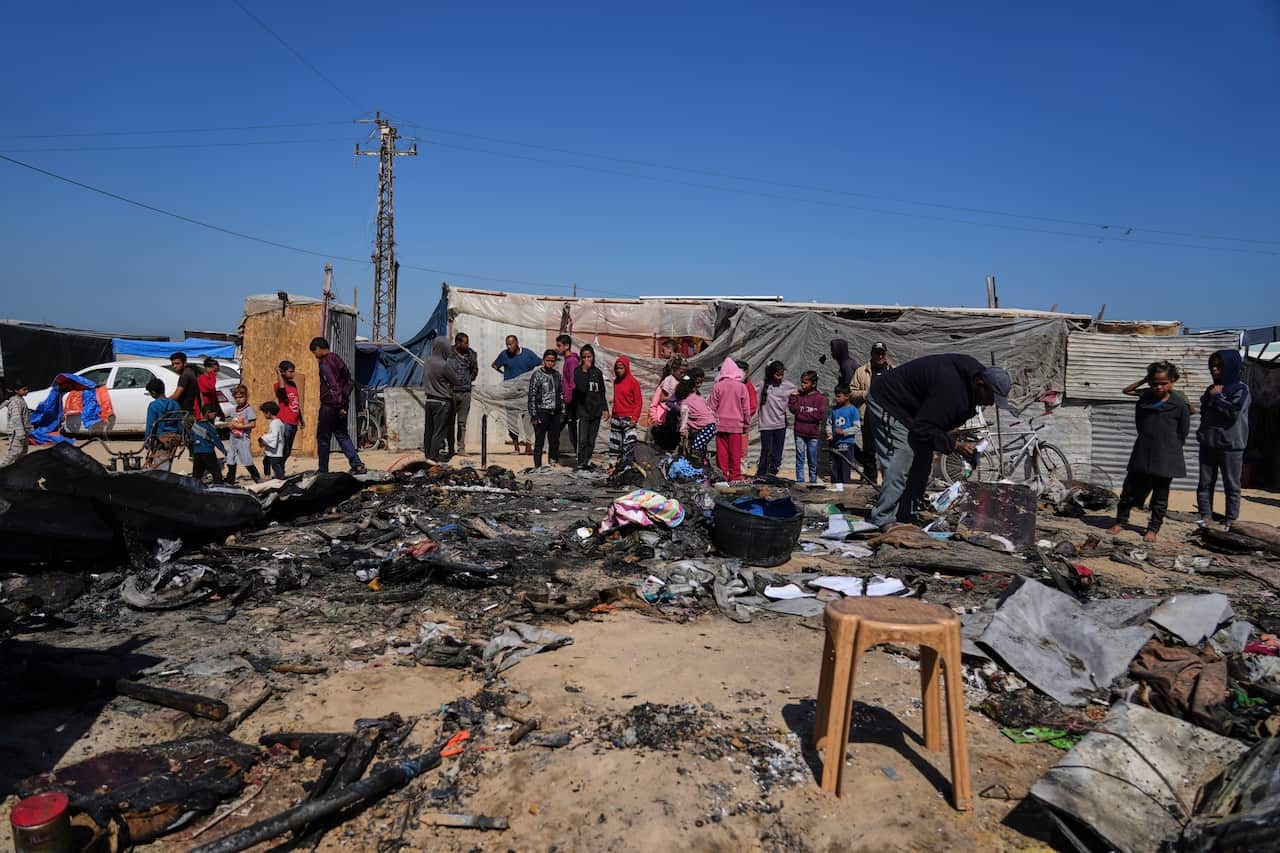 People inspect the remains of a displacement tent hit by an airstrike. 