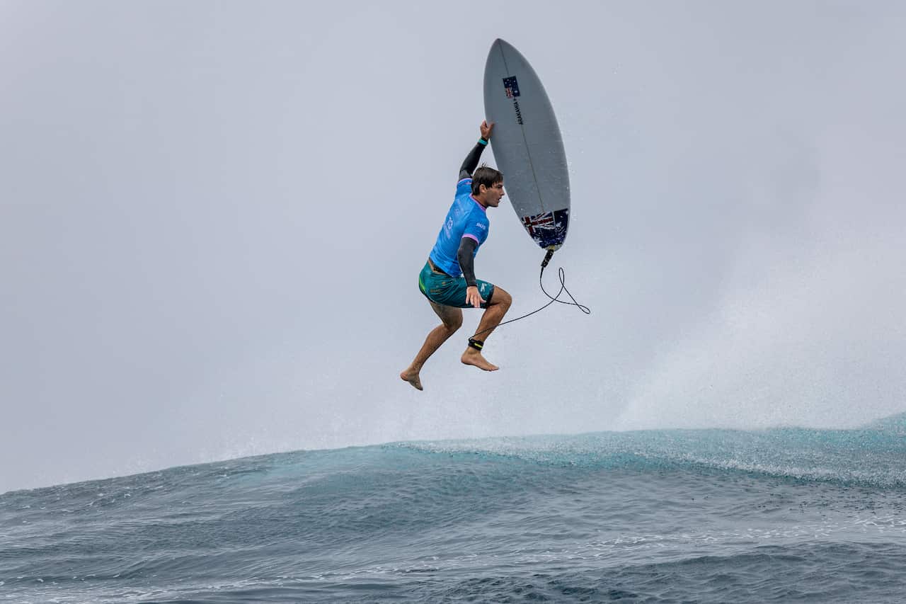 A man and his surfboard floating in mid-air after jumping off a wave 