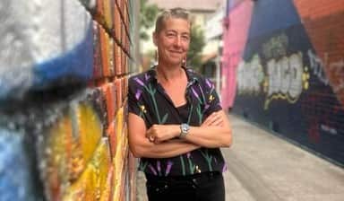 A woman against a bright-coloured wall.