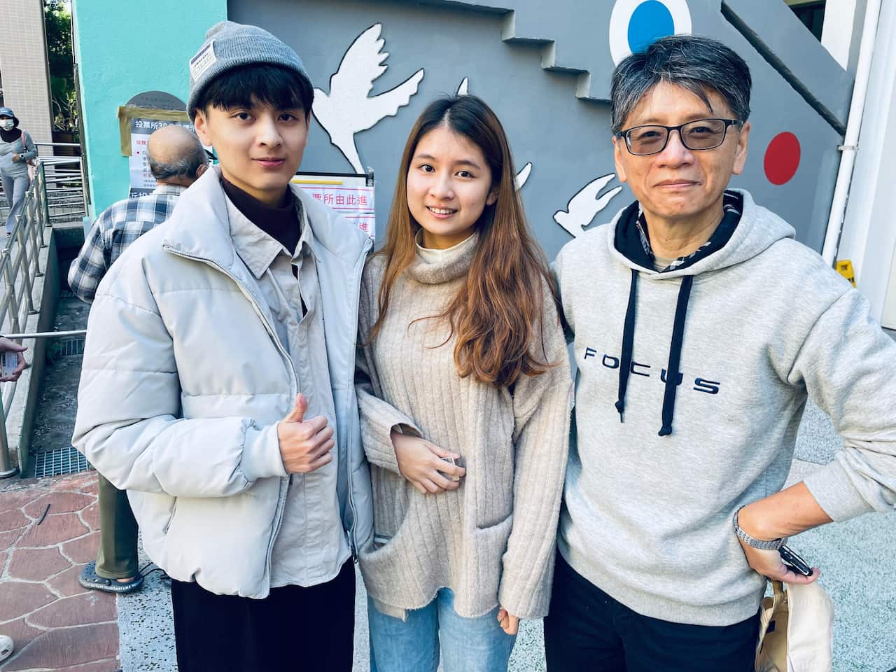 A brother and sister pose with their father outside the Taiwan voting centre.