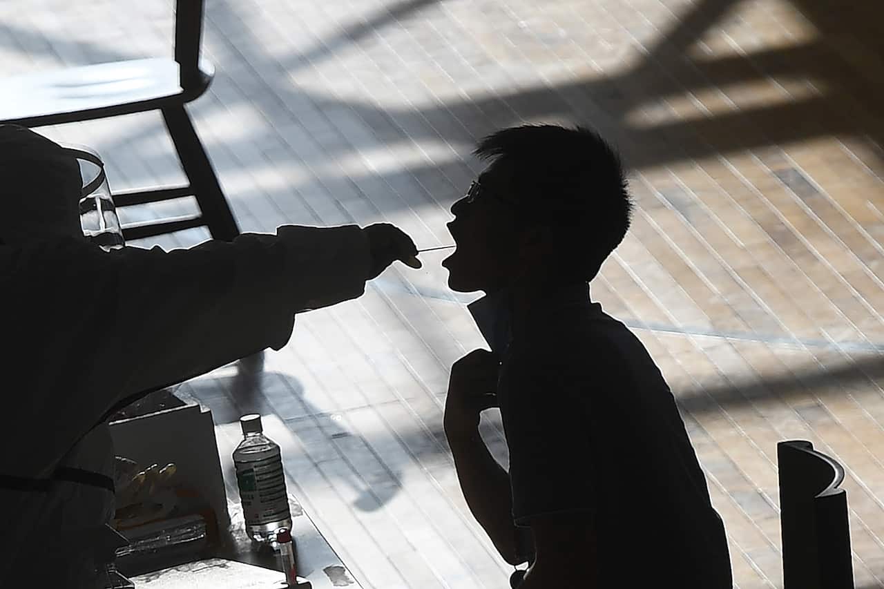 Silhouette showing a mouth swab being taken from a man for a COVID-19 test