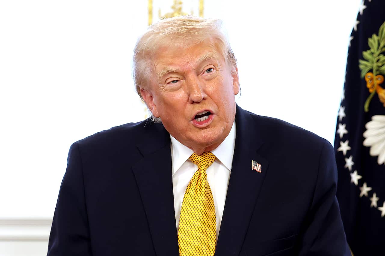 Donald Trump, in a black blazer, white shirt and yellow tie.