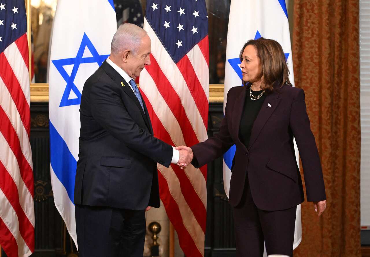 Benjamin Netanyahu and Kamala Harris shaking hands, with the Israeli and US flags in the background. 