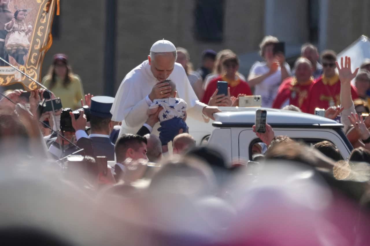 Pope Leo XIV kisses a baby's head as he tours St. Peter's Square at the Vatican
