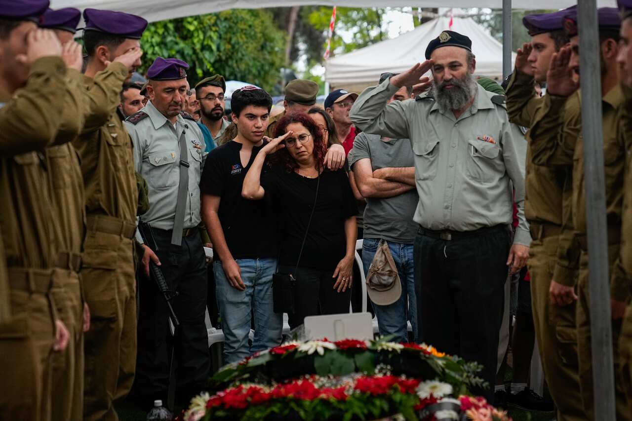 A crowd of people saluting a coffin wrapped in flowers
