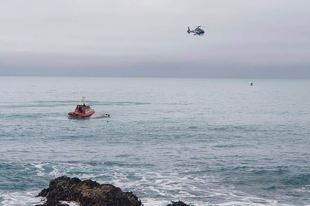 A helicopter and a rescue boat search for survivors off the coast of Kaikoura, New Zealand. 