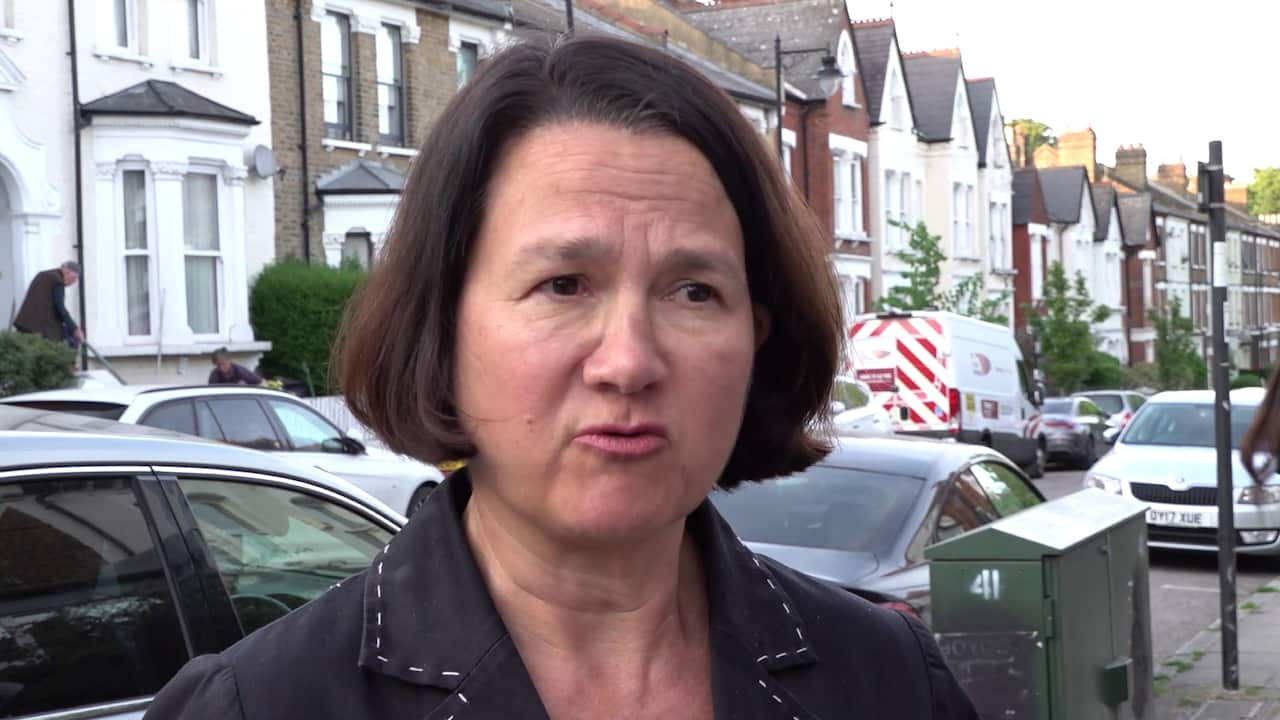 A middle-aged white woman with brown hair standing on a street