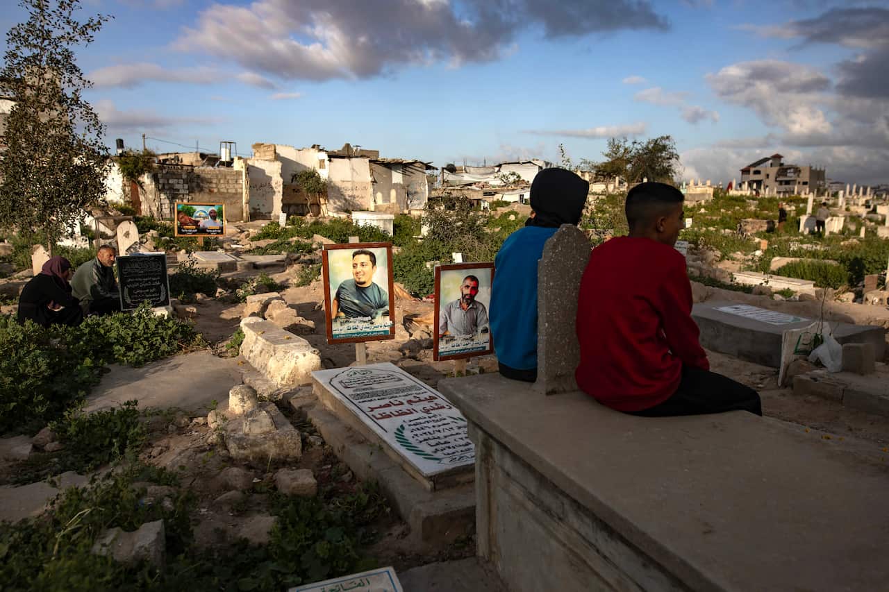 Two youths sit at a cemetary facing away from the camera