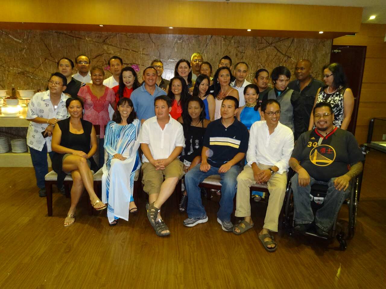 A group of about 25 Vietnamese adoptees pose for a photo in a wood-panelled room. 