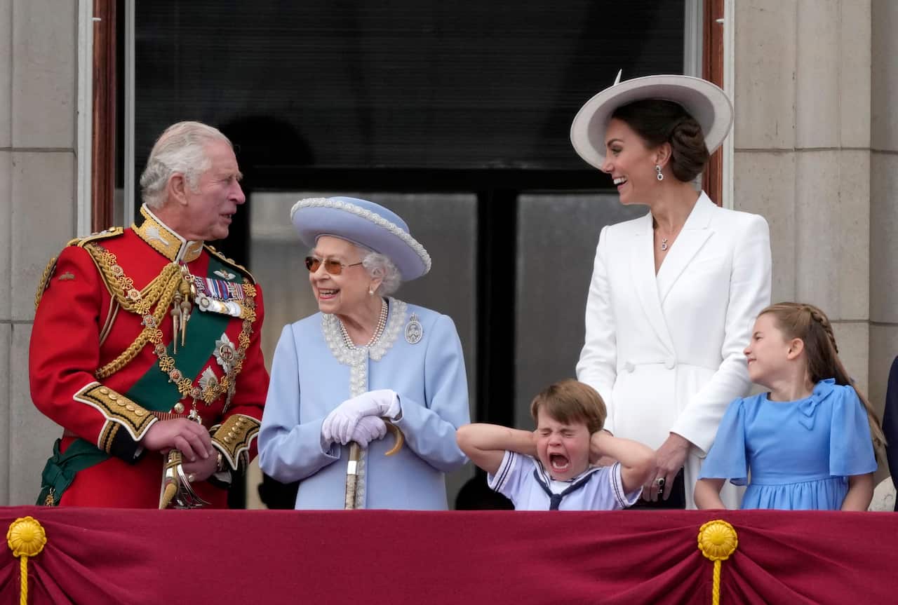 King Charles, Queen Camilla, Princess Kate and two of her children stand on the balcony at Buckingham Palace.
