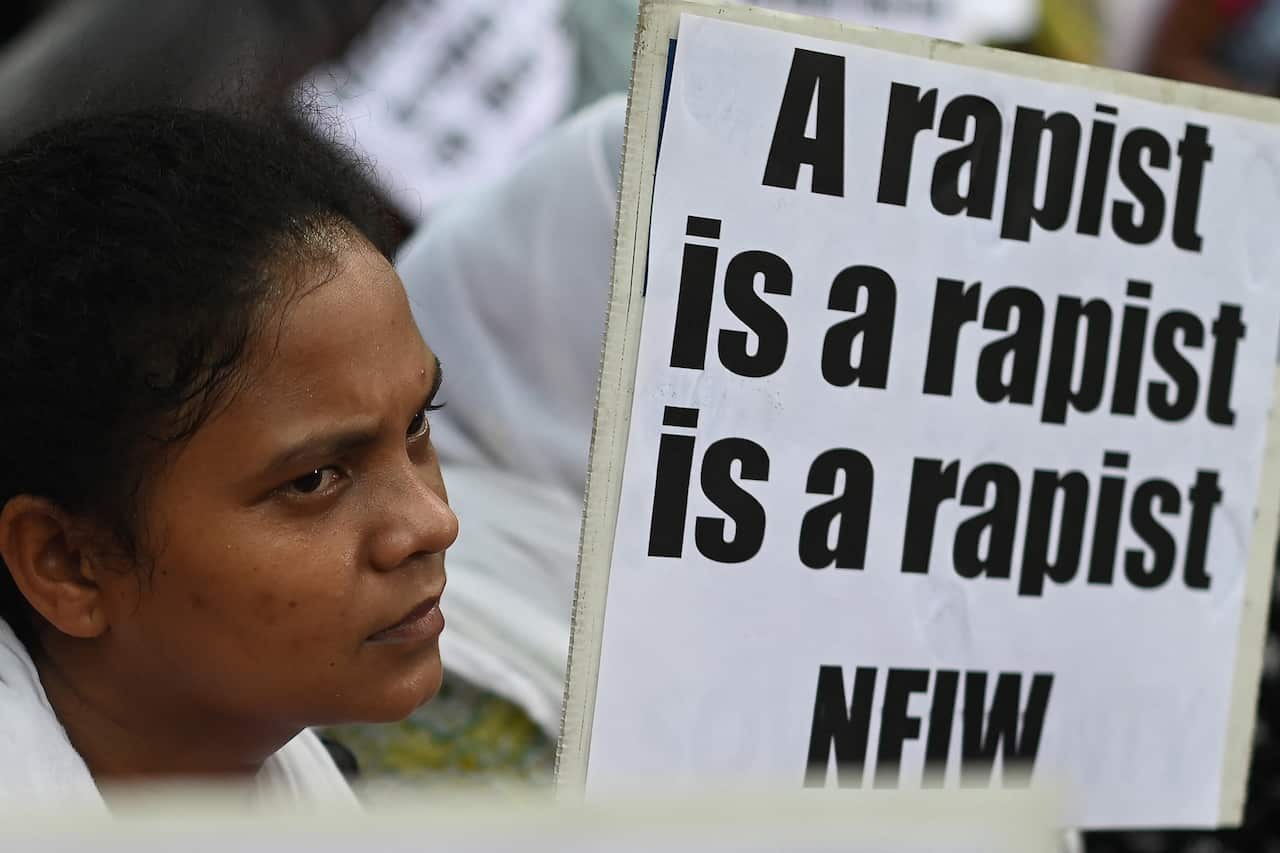 Woman holds a placard saying 'a rapist is a rapist is a rapist'