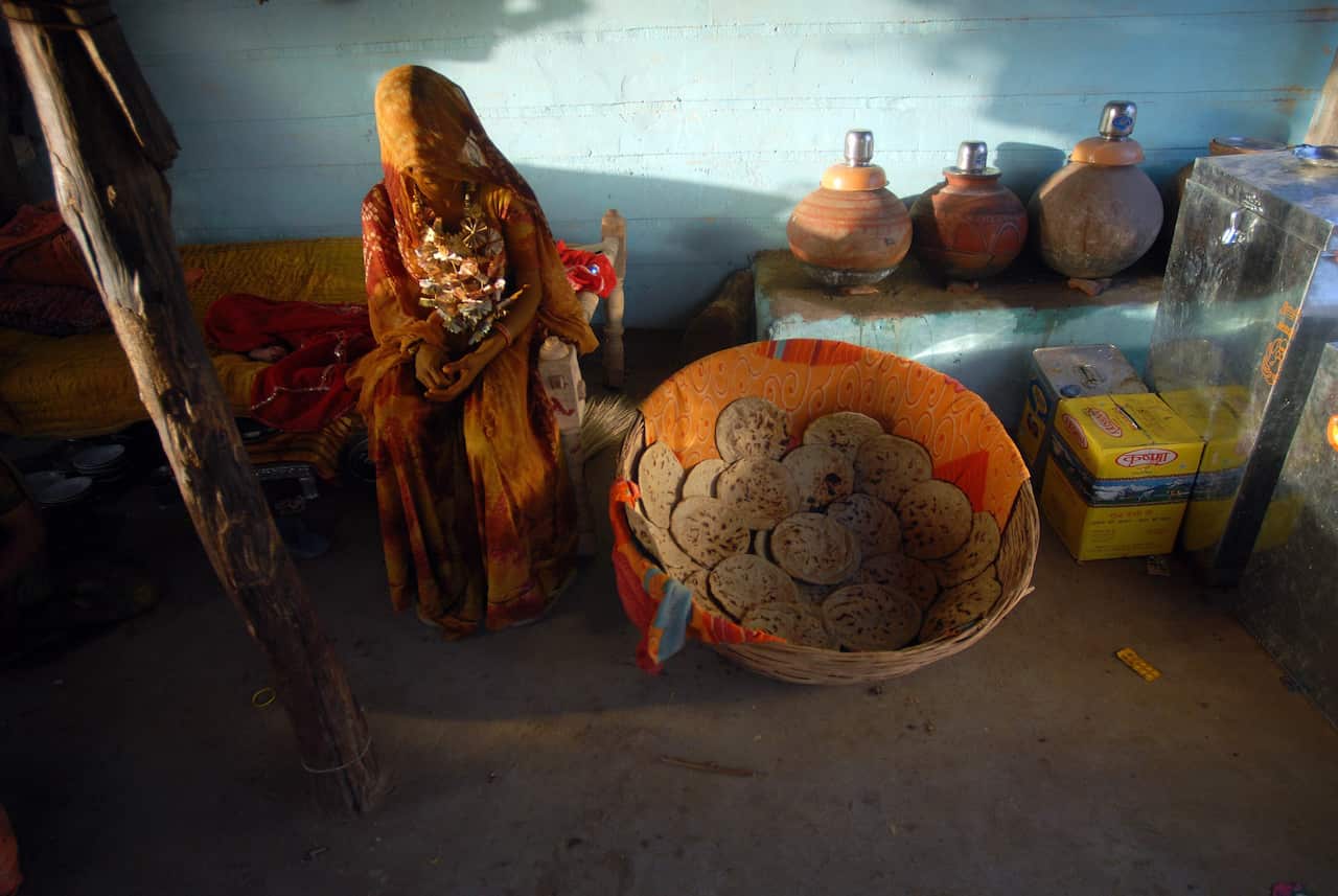 A young Indian bride with her face covered inside her home.