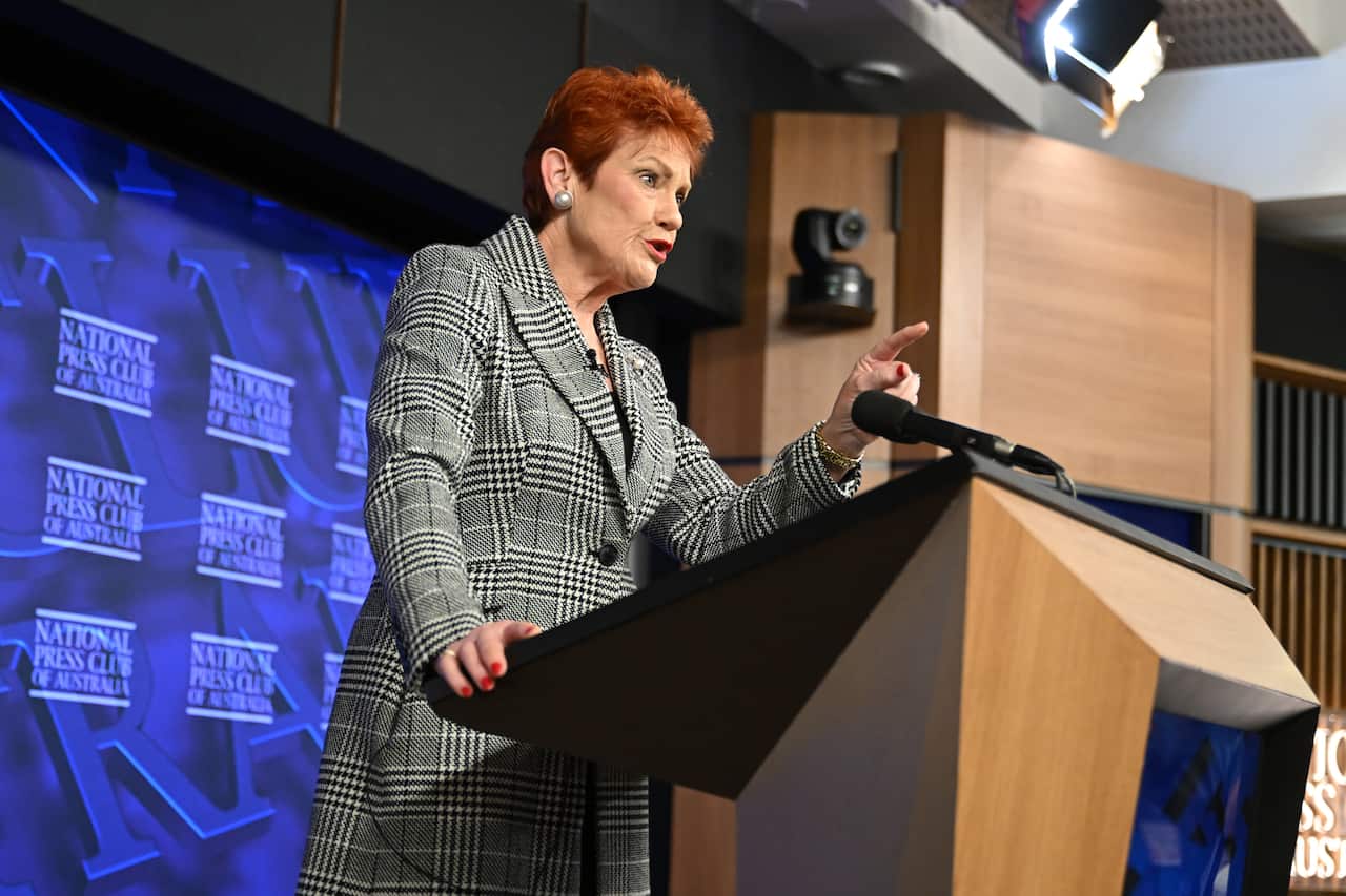 Pauline Hanson delivers her speech in a check coat with trademark red hair