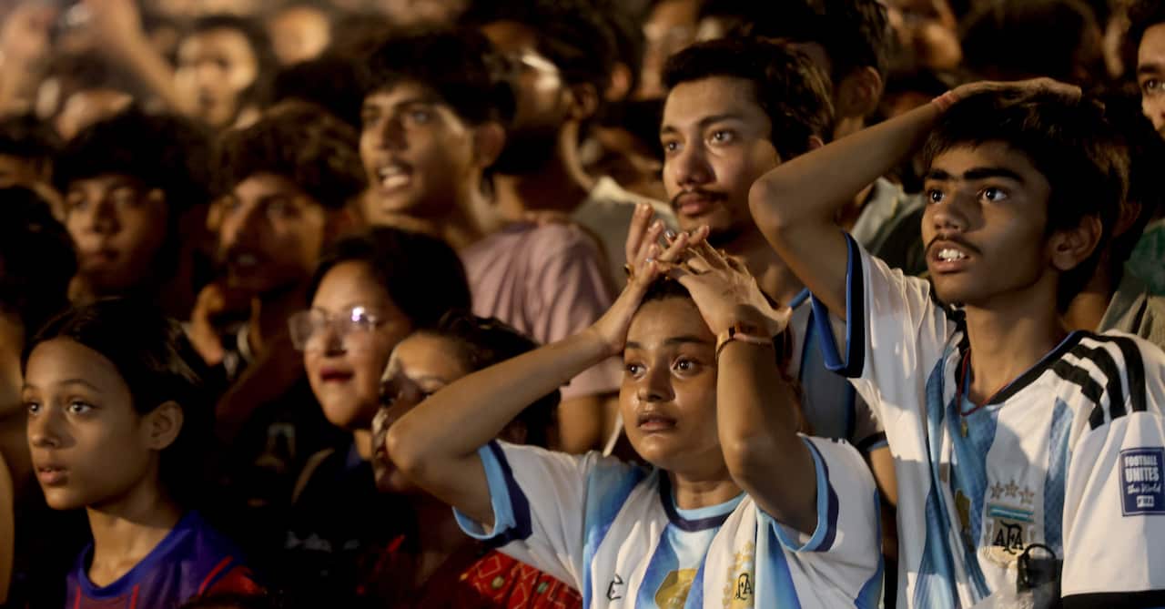 A group of football fans watch the 2026 World Cup final. Two people dressed in Argentina shirts put their hands ot their heads in dismay.