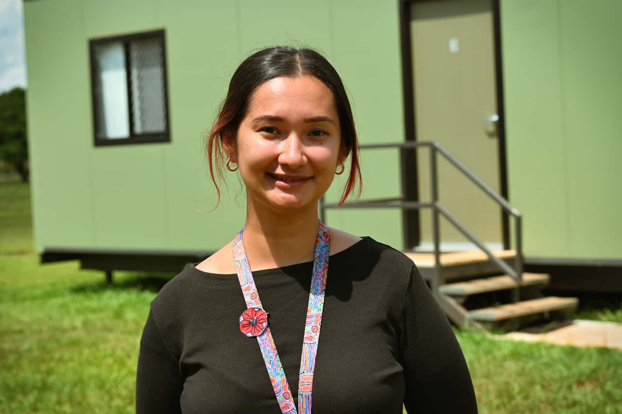 A woman stands outside a demountable classroom