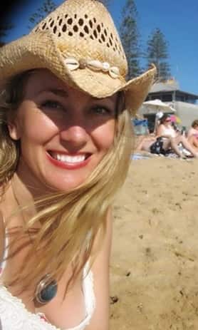 Allannah Law sitting on the beach smiling at the camera. 