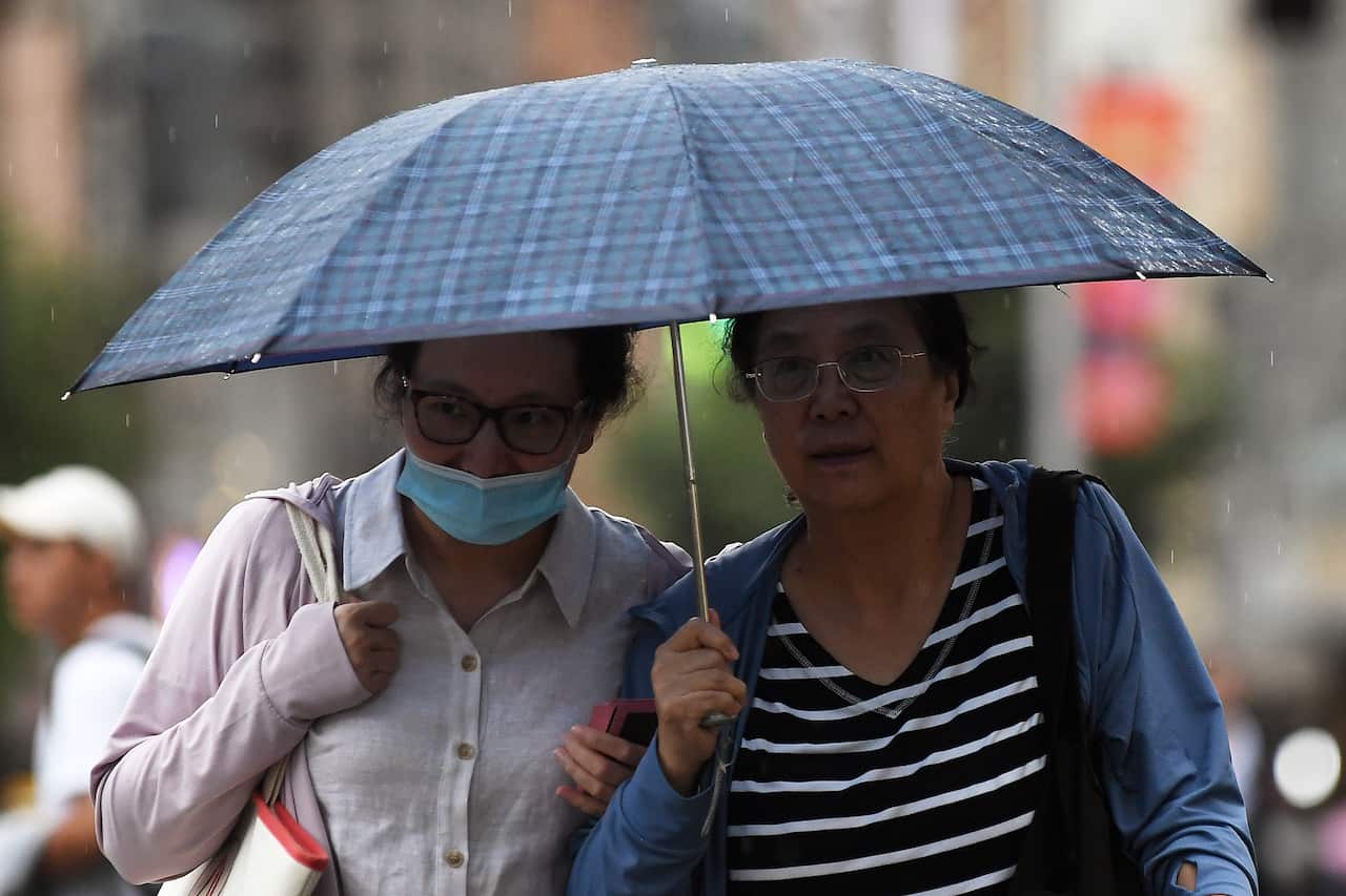 Two women walking outside under an umbrella