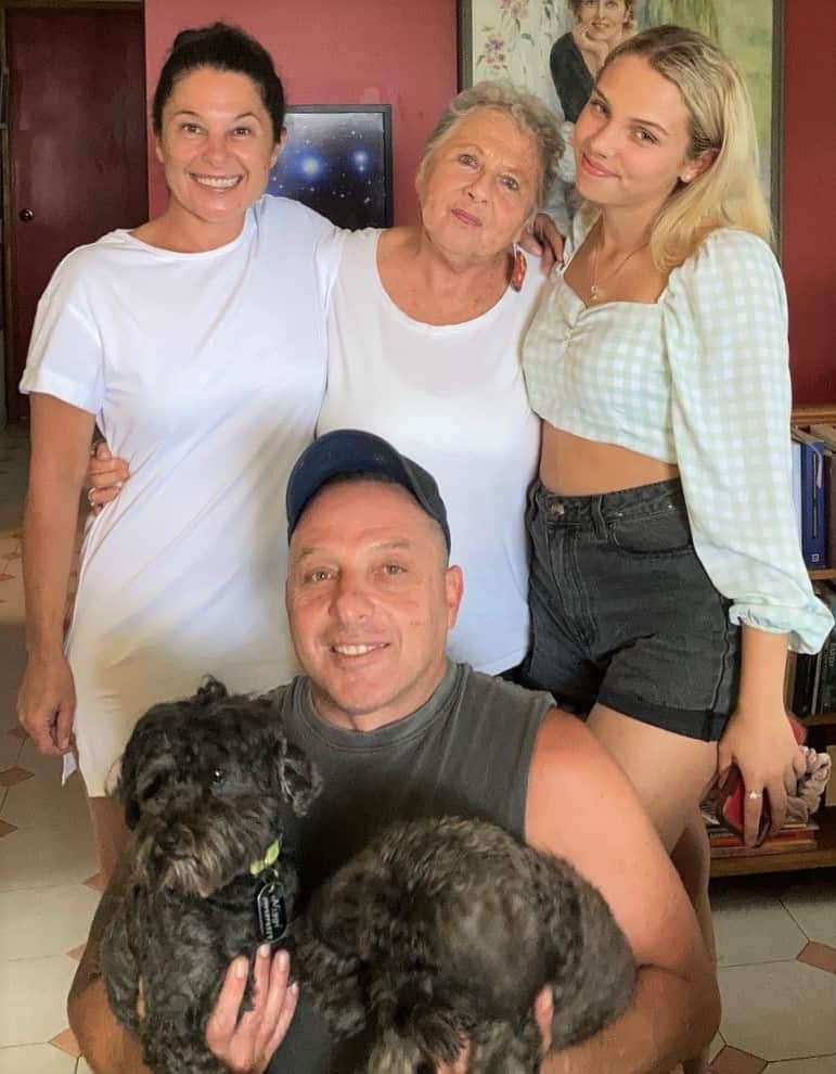 A woman standing in between her children and granddaughter.