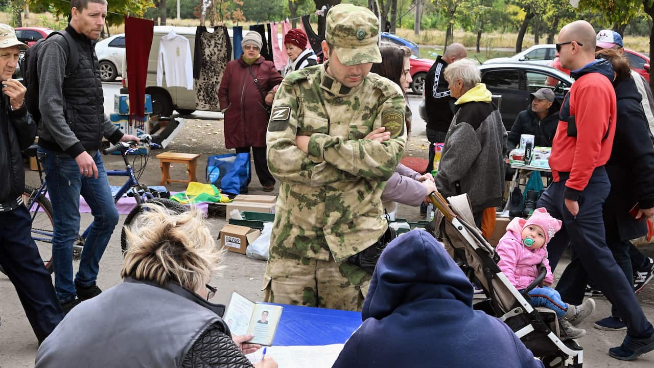 A soldier supervises residents casting votes at a table.