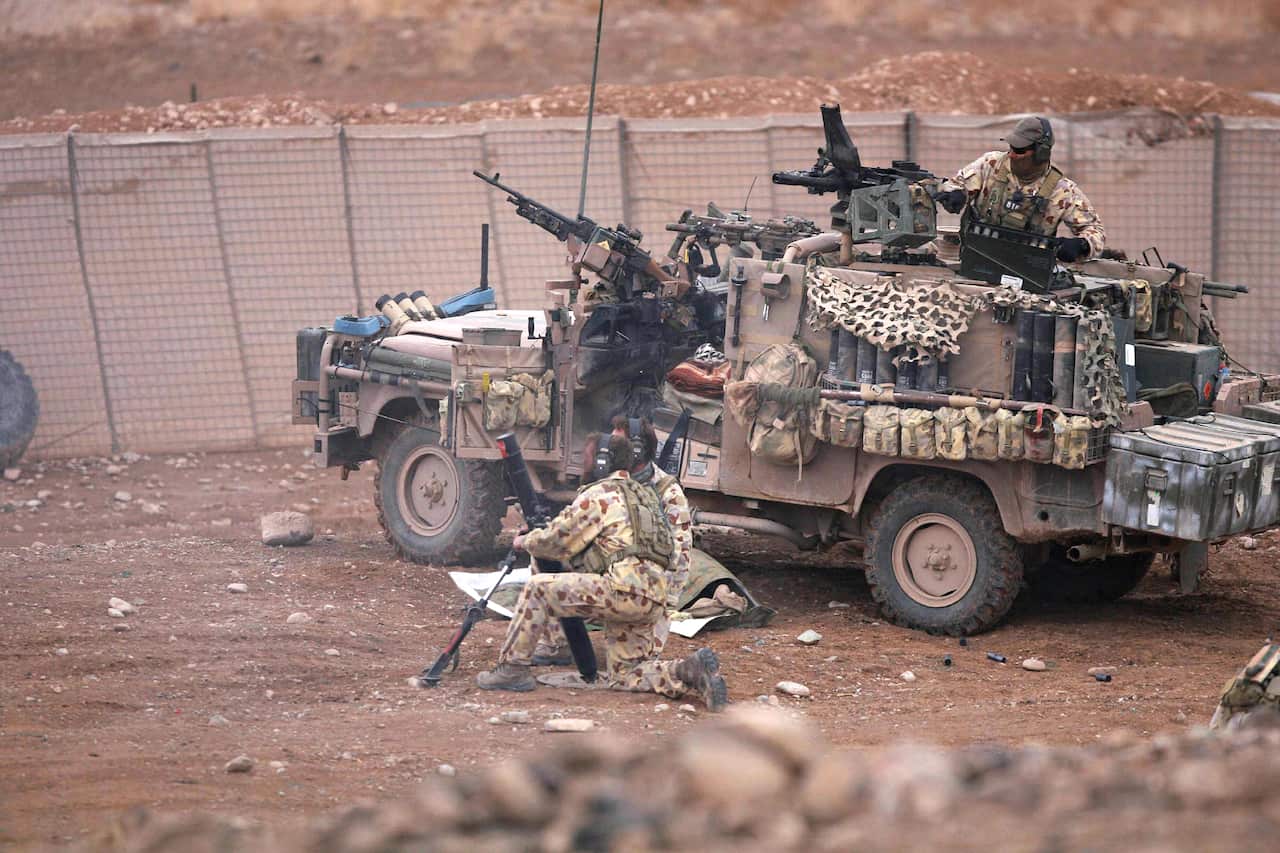 Soldiers standing on and around an army vehicle.