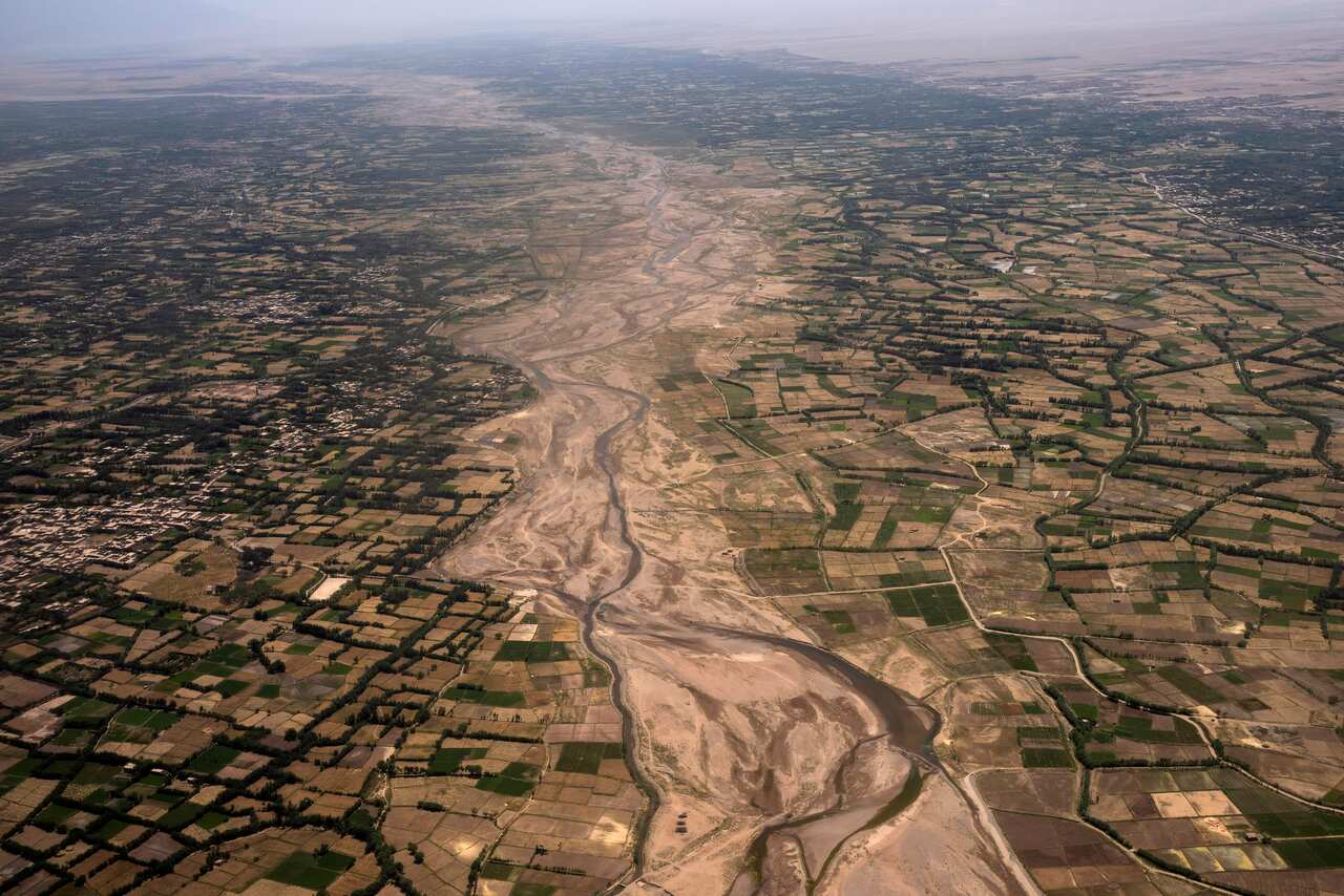 An aerial view of the outskirts of Herat, Afghanistan, shows a sandy river and farmland. 